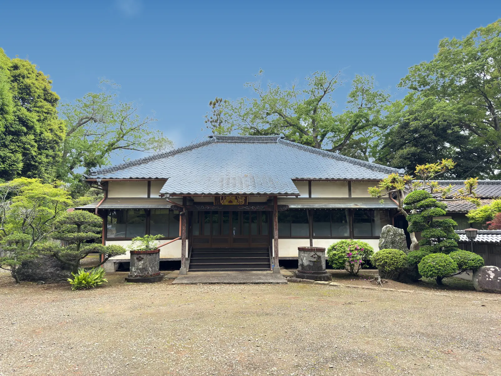 満願寺の本堂。青空の下、新緑に囲まれた瓦屋根のお堂